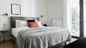 A bedroom with a large bed, a bedside table, a lamp, and a view of greenery outside. - Striking 1BR Apartment in Kolonaki A (Athens)