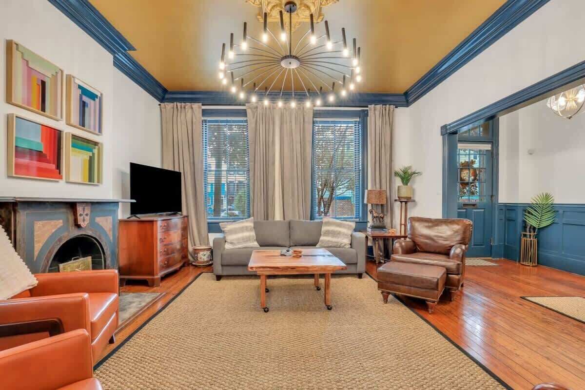 A living room with a fireplace, a television, a sofa, a coffee table, and a chandelier.