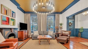 Una sala de estar con chimenea, televisor, sofá, mesa de centro y candelabro.