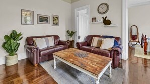 A living room with two leather sofas, a wooden coffee table, and a large potted plant.