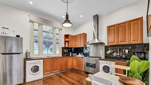 A modern kitchen with wooden cabinets, stainless steel appliances, and a large window.