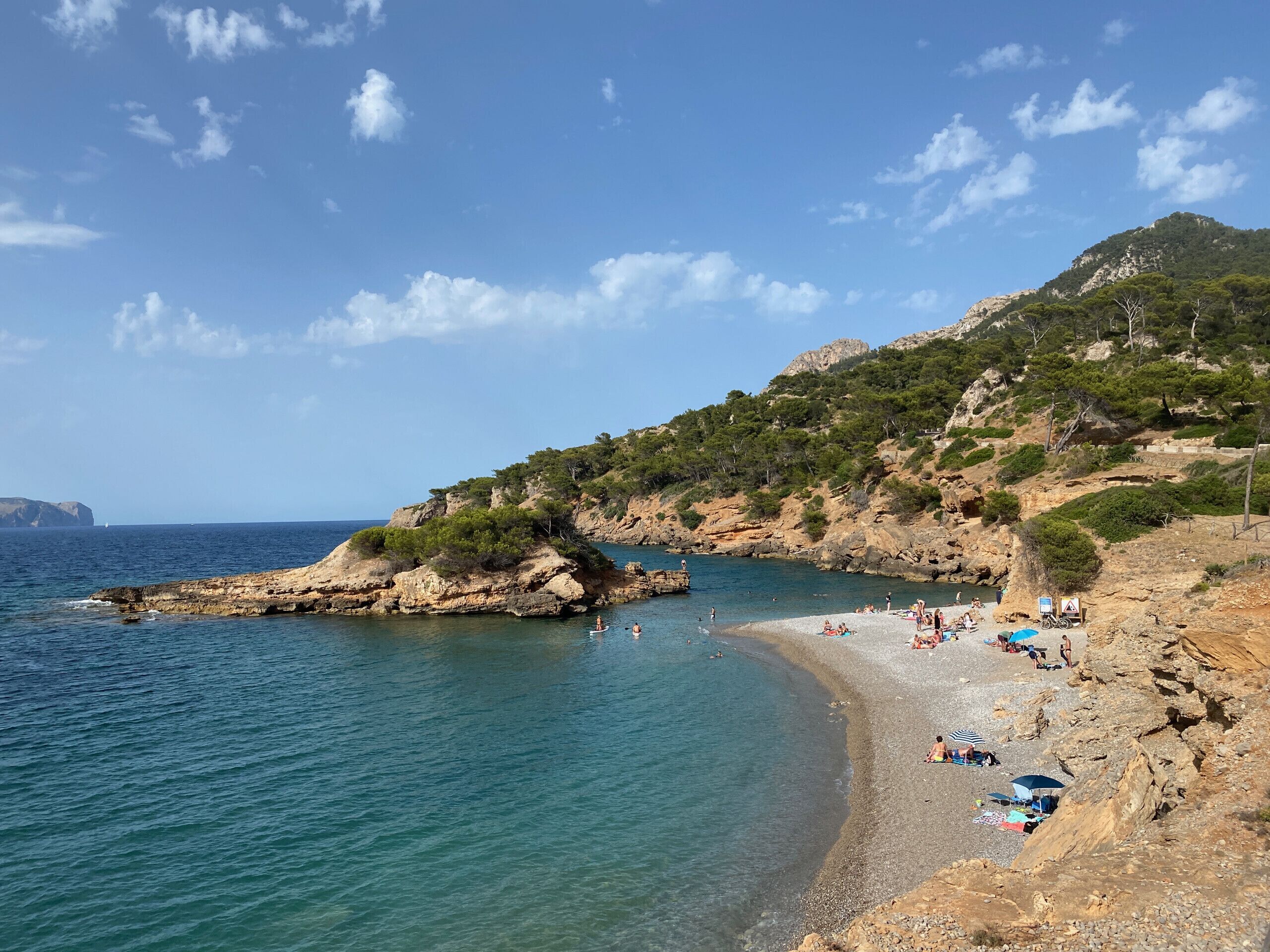 A coastal beach with rocky terrain and clear blue waters.