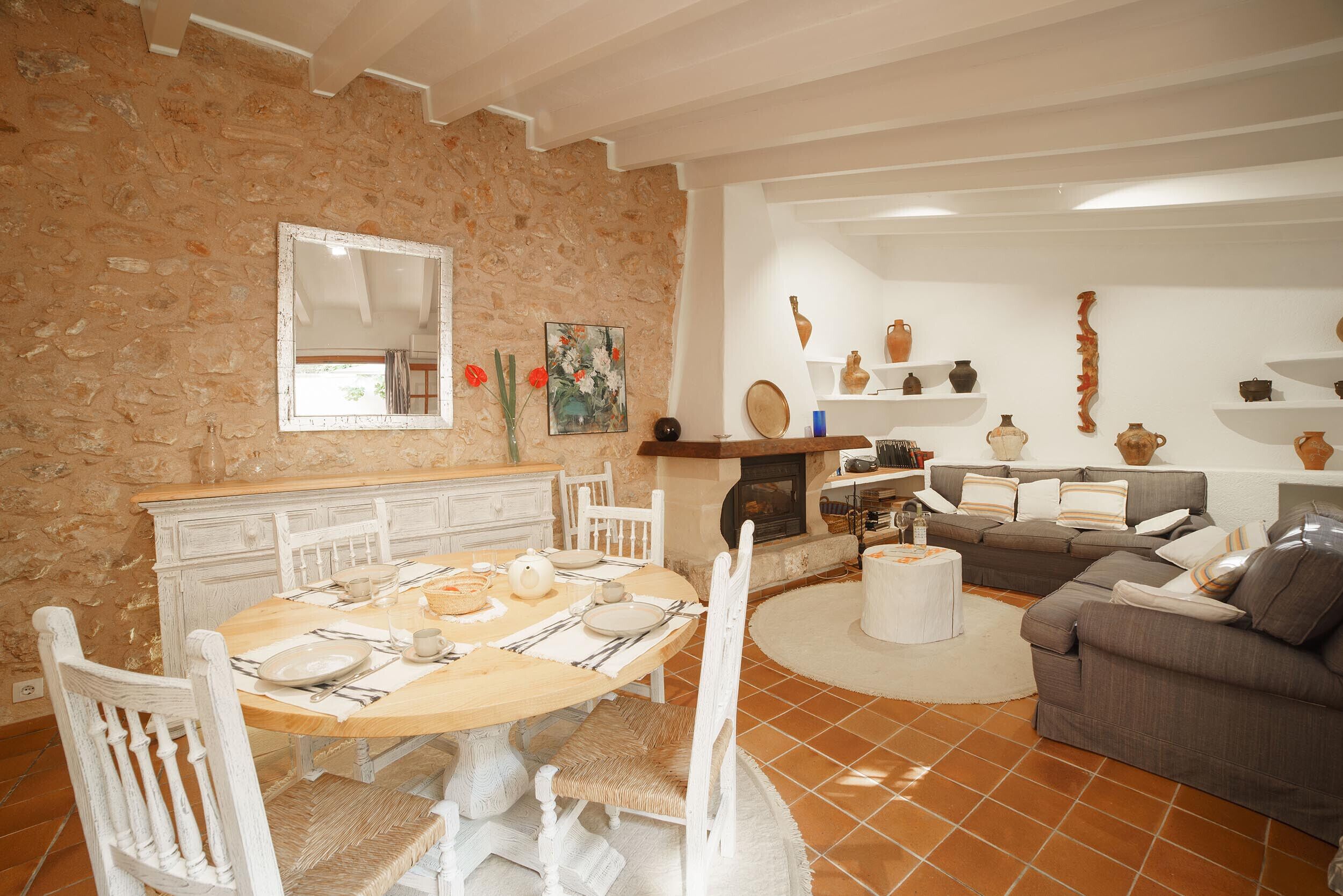Ein Essbereich mit Steinwand, Kamin und ein Wohnzimmer mit Sofa und Dekoration.