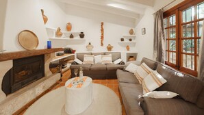 A living room with a fireplace, a sofa, a coffee table, and shelves with decorative items. - Townhouse Calvario at Calvari (Pollensa / Pollença)