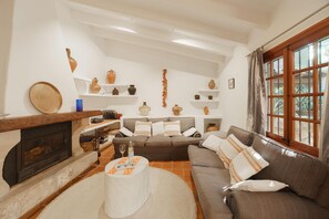 A living room with a fireplace, a sofa, a coffee table, and shelves with decorative items. - Townhouse Calvario at Calvari (Pollensa / Pollença)