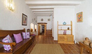 A cozy living room with a wooden sofa, a small wooden table, and a staircase leading to another room. - Townhouse Calvario at Calvari (Pollensa / Pollença)