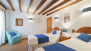A room with two beds, a chair, and a wooden ceiling. - Townhouse Calvario at Calvari (Pollensa / Pollença)