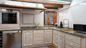A kitchen with wooden cabinets, a Bosch dishwasher, a microwave, and a sink. - Townhouse Calvario at Calvari (Pollensa / Pollença)