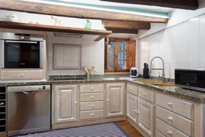 A kitchen with wooden cabinets, a Bosch dishwasher, a microwave, and a sink. - Townhouse Calvario at Calvari (Pollensa / Pollença)