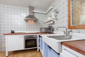 A compact kitchen with white cabinets, a built-in oven, a microwave, and a sink.