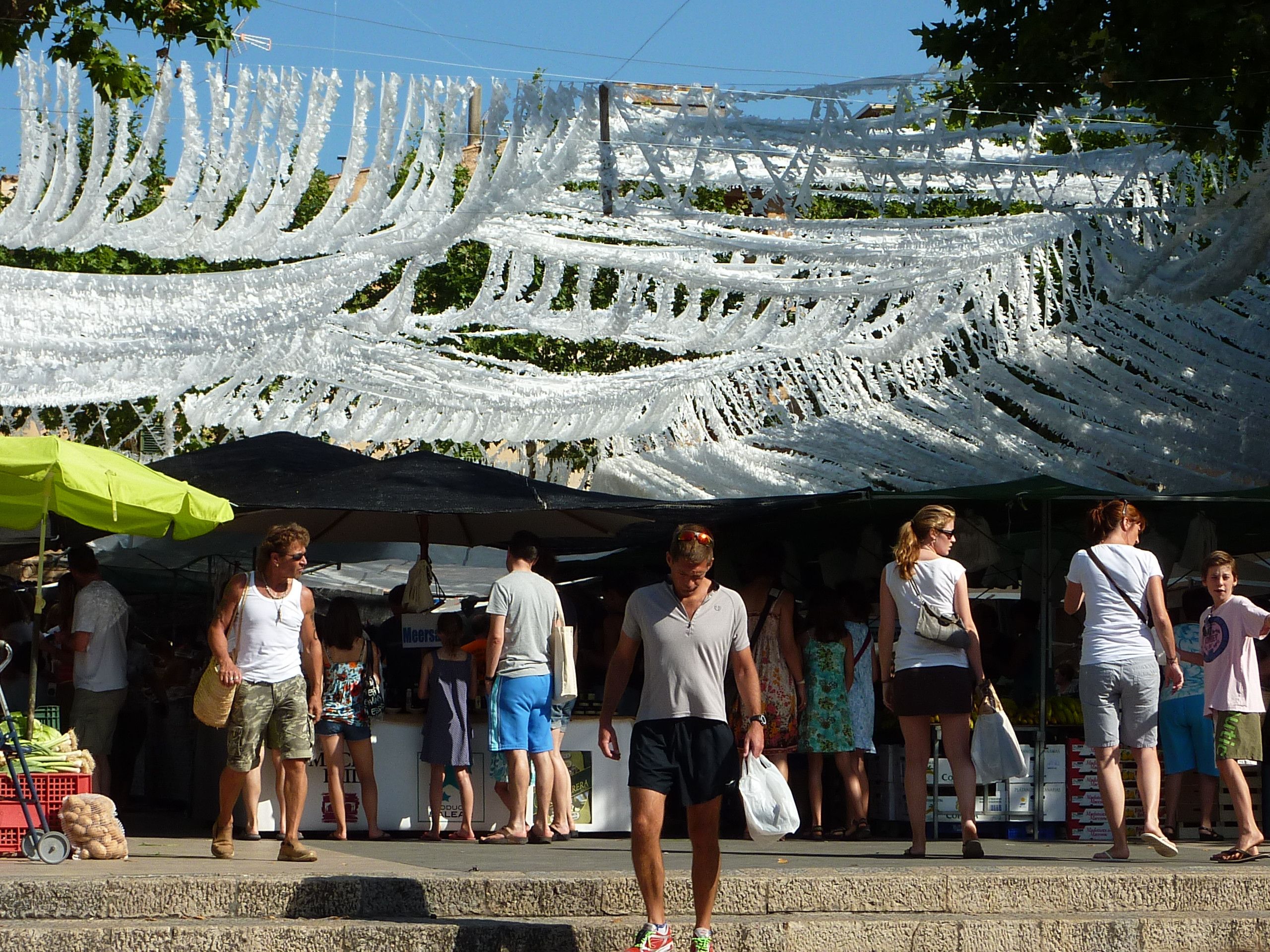 A market with people standing under a white canopy.
