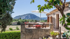 Un espacio de patio con mobiliario exterior, una sombrilla blanca y plantas en macetas.
