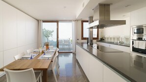 Una cocina moderna con electrodomésticos de acero inoxidable, un comedor con mesa de madera y vistas a un balcón.