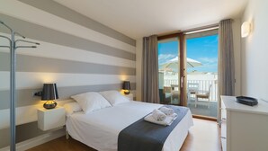 Habitación de hotel con una cama grande, dos lámparas de noche, un escritorio y vistas al balcón exterior.