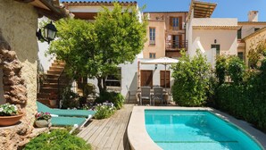 A pool area with a curved pool, wooden deck, and outdoor seating.
