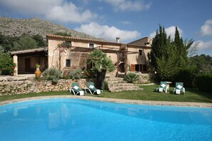 A stone villa with a swimming pool, outdoor seating, and a mountainous backdrop. - Holiday Rental Can Colonya in Majorca Ternelles (Pollensa / Pollença)