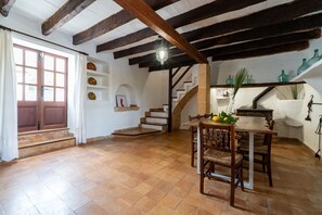 Ein geräumiger Essbereich mit Holztisch und Stühlen, eine Treppe, die zu einer oberen Ebene führt, und ein Blick ins Freie durch ein großes Fenster.