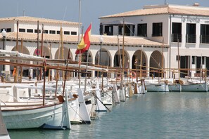 A marina with multiple boats docked, a building with arched windows, and a flag.