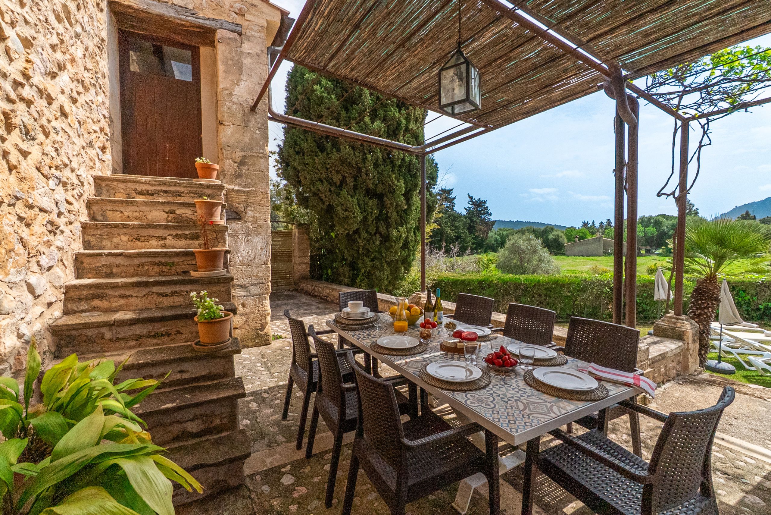 An outdoor dining area with a stone staircase, wicker chairs, and a table set for four.