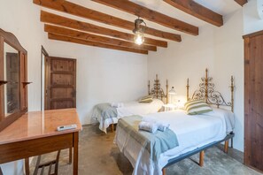 Ein Schlafzimmer mit zwei Betten, Holzbalken an der Decke, einem Nachttisch und einem Holzschrank.