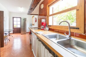 A kitchen with two sinks, a coffee maker, and a window with a view of greenery. - Holiday Rental Can Colonya in Majorca Ternelles (Pollensa / Pollença)