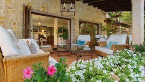 A cozy outdoor seating area with wicker furniture, a glass coffee table, and a stone wall backdrop. - Majorca Villa with pool in Majorca - Villa Font (Mancor de la Vall)