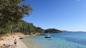 En strand med klart vatten, folk som solar och en båt.