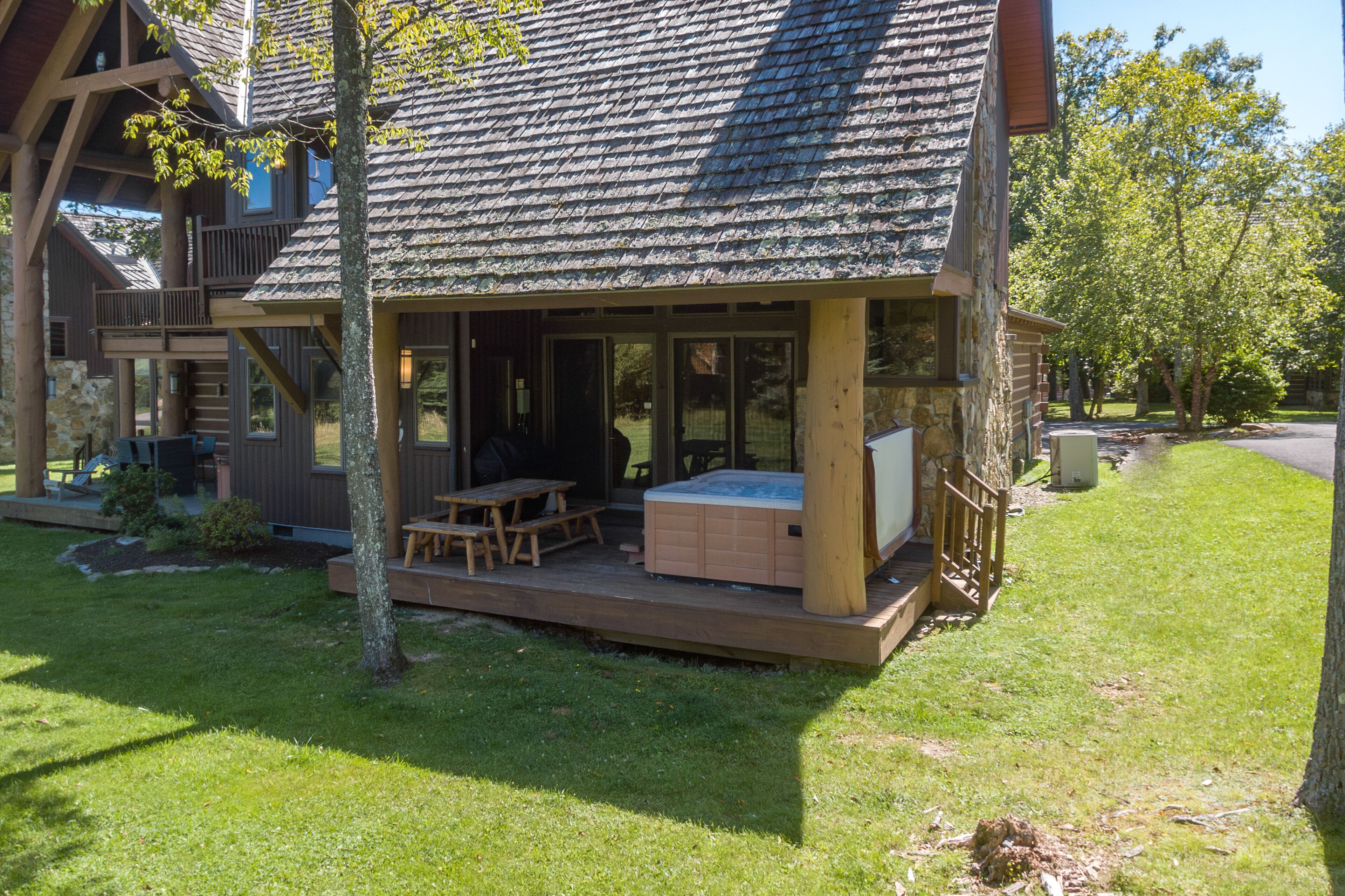 Un chalet doté d’une terrasse couverte, de meubles de jardin et d’un bain à remous.