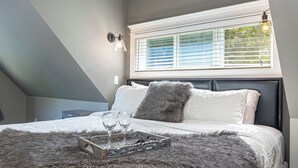 Un dormitorio con una cama grande, una ventana con persianas, una mesita de noche y una lámpara.