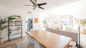 Una sala moderna con una mesa de comedor de madera, un sofá blanco y un ventilador de techo.