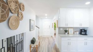 Una cocina moderna con armarios blancos, una cafetera y una planta en la encimera.