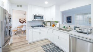 Una cocina moderna con armarios blancos, electrodomésticos de acero inoxidable y un ventanal grande.