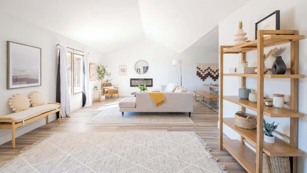 Una sala de estar moderna con un sofá blanco, estanterías de madera y un ventanal grande.