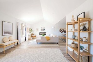 Un salon moderne avec un canapé blanc, des étagères en bois et une grande fenêtre.