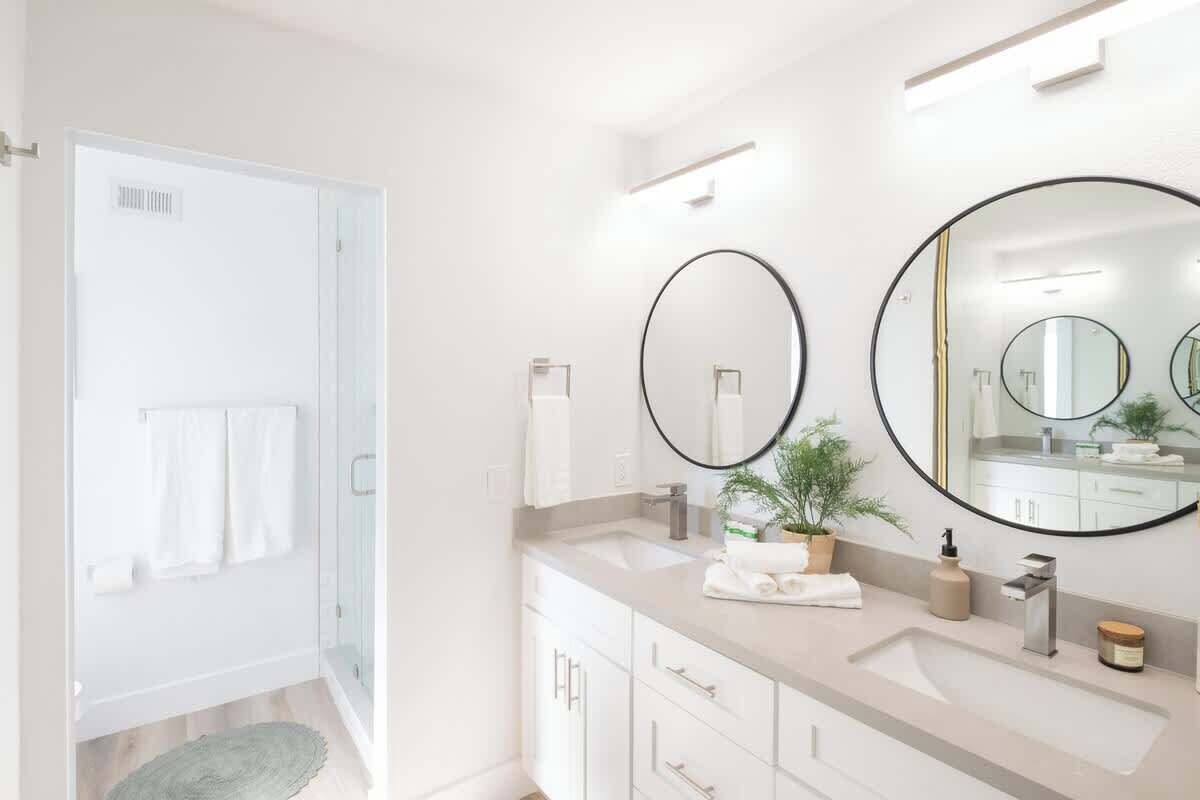 A modern bathroom with a large mirror, a sink, and a shower area.