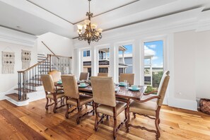 A dining area with a wooden table, six chairs, and a chandelier.