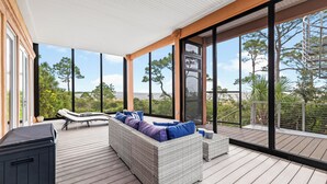 Una terraza moderna al aire libre con un sofá de mimbre, sillones de descanso y un jacuzzi.