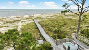 Una terraza de madera que da a una playa con un jacuzzi.