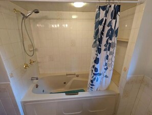 Een bad/douchecombinatie, handdoeken, zeep, shampoo