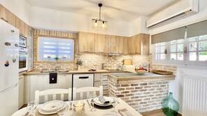 A modern kitchen with a brick backsplash, wooden cabinets, and a dining area set for six.