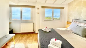 A bedroom with a bed, two windows, a radiator, a wooden floor, and a hanging light fixture.
