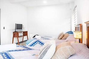 Ein Hotelzimmer mit zwei Betten, einem Schreibtisch, einem Fernseher und einer Lampe.