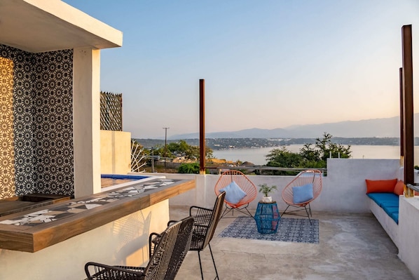 Eine Terrasse mit Meerblick, ausgestattet mit einer Bar, Sitzgelegenheiten und dekorativen Fliesen.