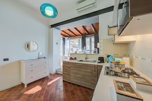 Eine Küche mit Gasherd, Spüle, weißer Arbeitsplatte und einem Fenster mit Vorhängen.