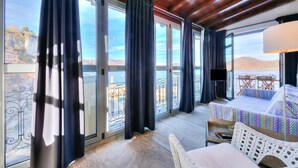 A room with a large window, a bed, a TV, and a balcony with a table and chairs. - Stella Del Lago Pied Dans L'eau in Arona (Arona)