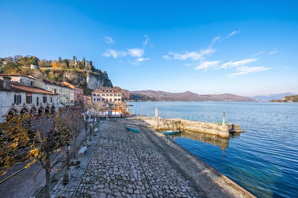 A coastal town with stone buildings, a waterfront promenade, and a lighthouse.