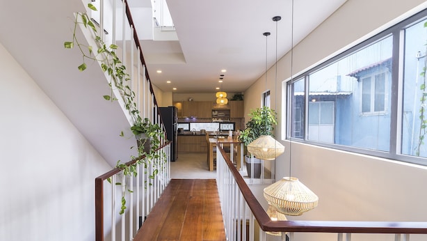 Un interior moderno con una escalera de madera, una zona de cocina y ventanas amplias.