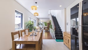 Una cocina moderna con una mesa de comedor de madera, lámparas colgantes y una escalera que conduce a un nivel superior.