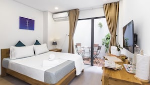 Una habitación de hotel con una cama, un escritorio con computadora, una silla, una mesa y una ventana con cortinas.