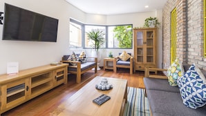 Una sala de estar acogedora con una mesa de centro de madera, un sofá y un televisor montado en la pared.